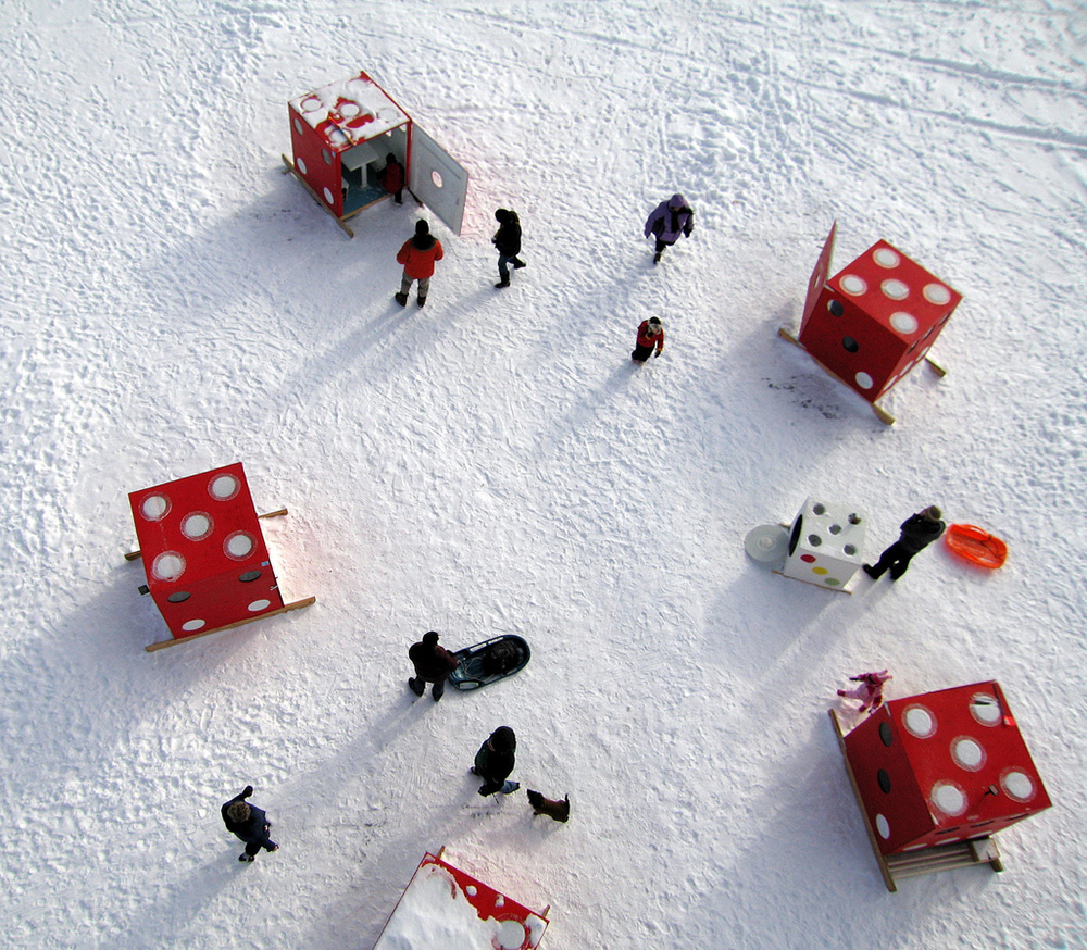 a bird's eye view of three dice shaped shanties with several people walking between them