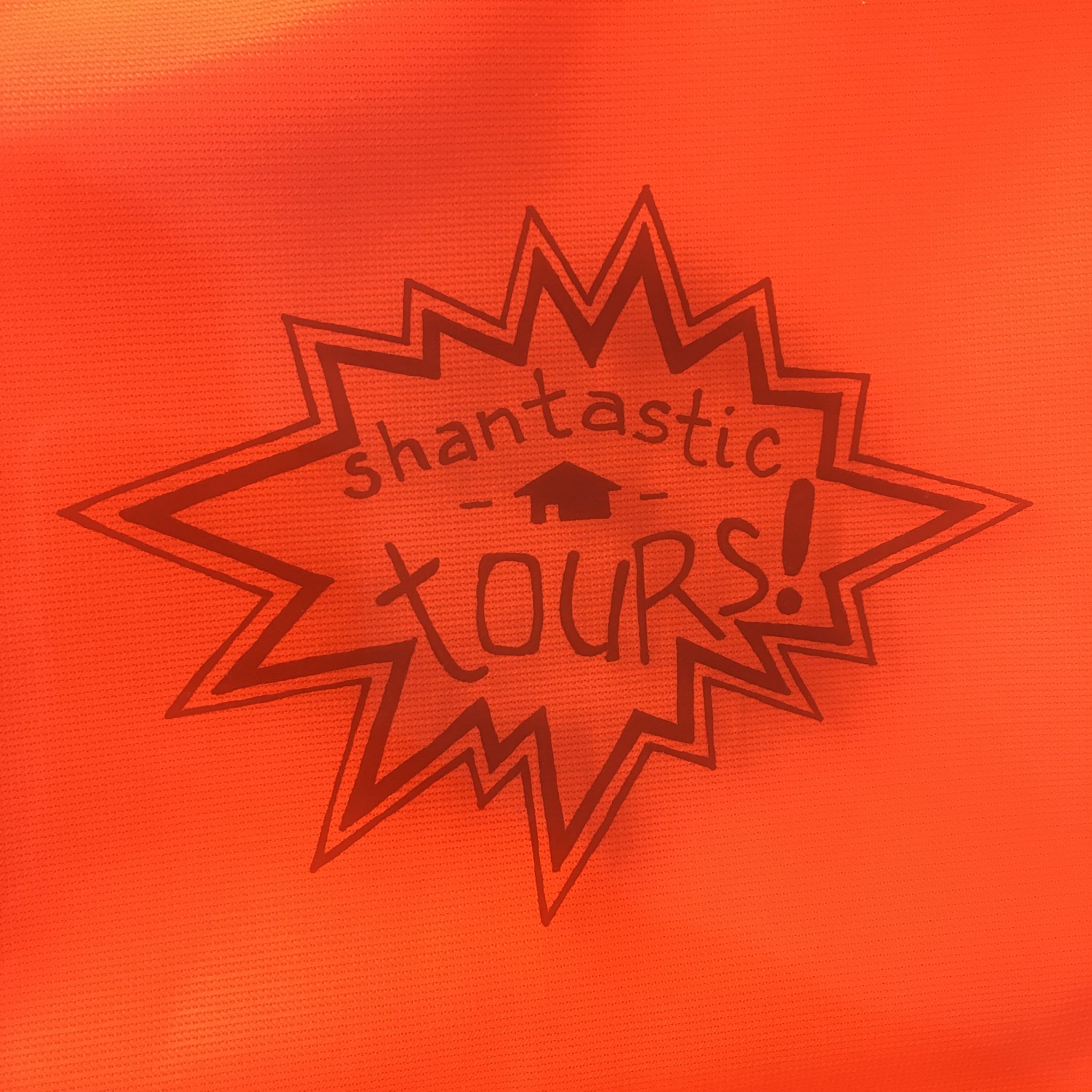 On a saturated orange-red background, cartoon POW-style explosion with the words "shantastic tours!" written inside.