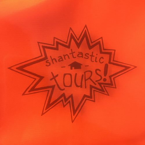 On a saturated orange-red background, cartoon POW-style explosion with the words "shantastic tours!" written inside.