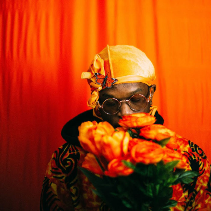 Photo of a person with orange flowers, orange headpiece and orange background