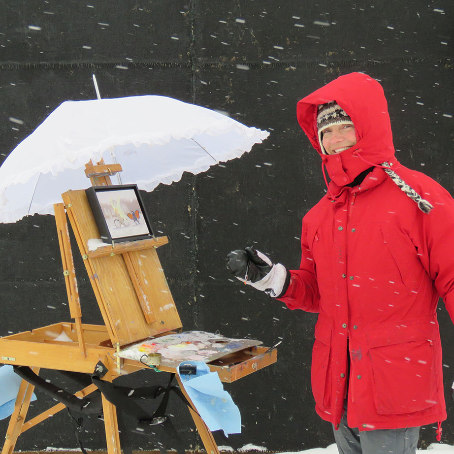 Photo of a person painting at an easel outside in the snow