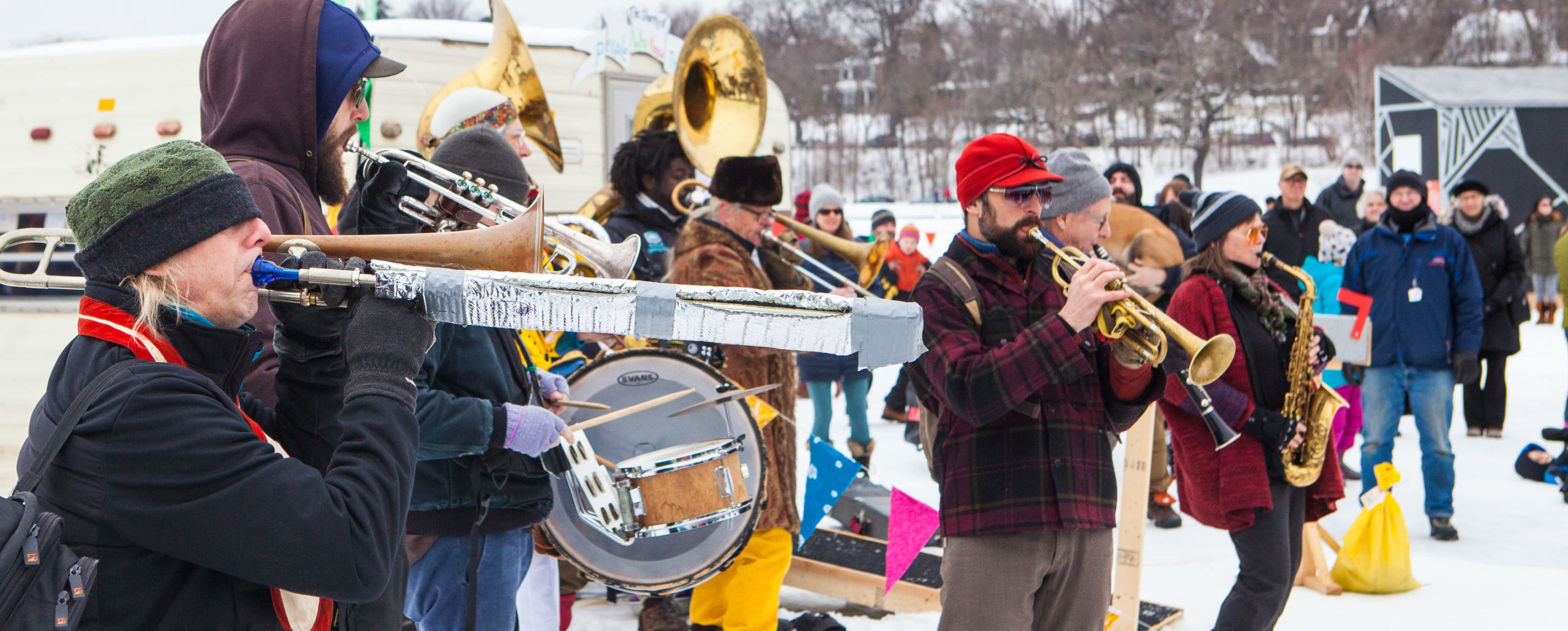 A brass band plays their horns amidst a colorful village on a frozen lake.