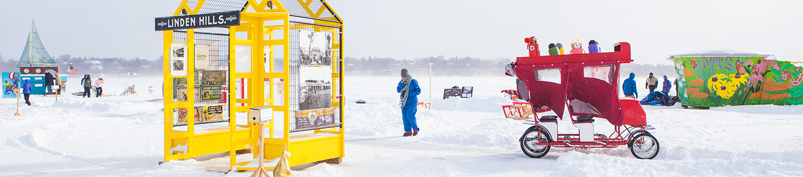 A red bicycle surrey rides through the colorful shanty village on the frozen lake.