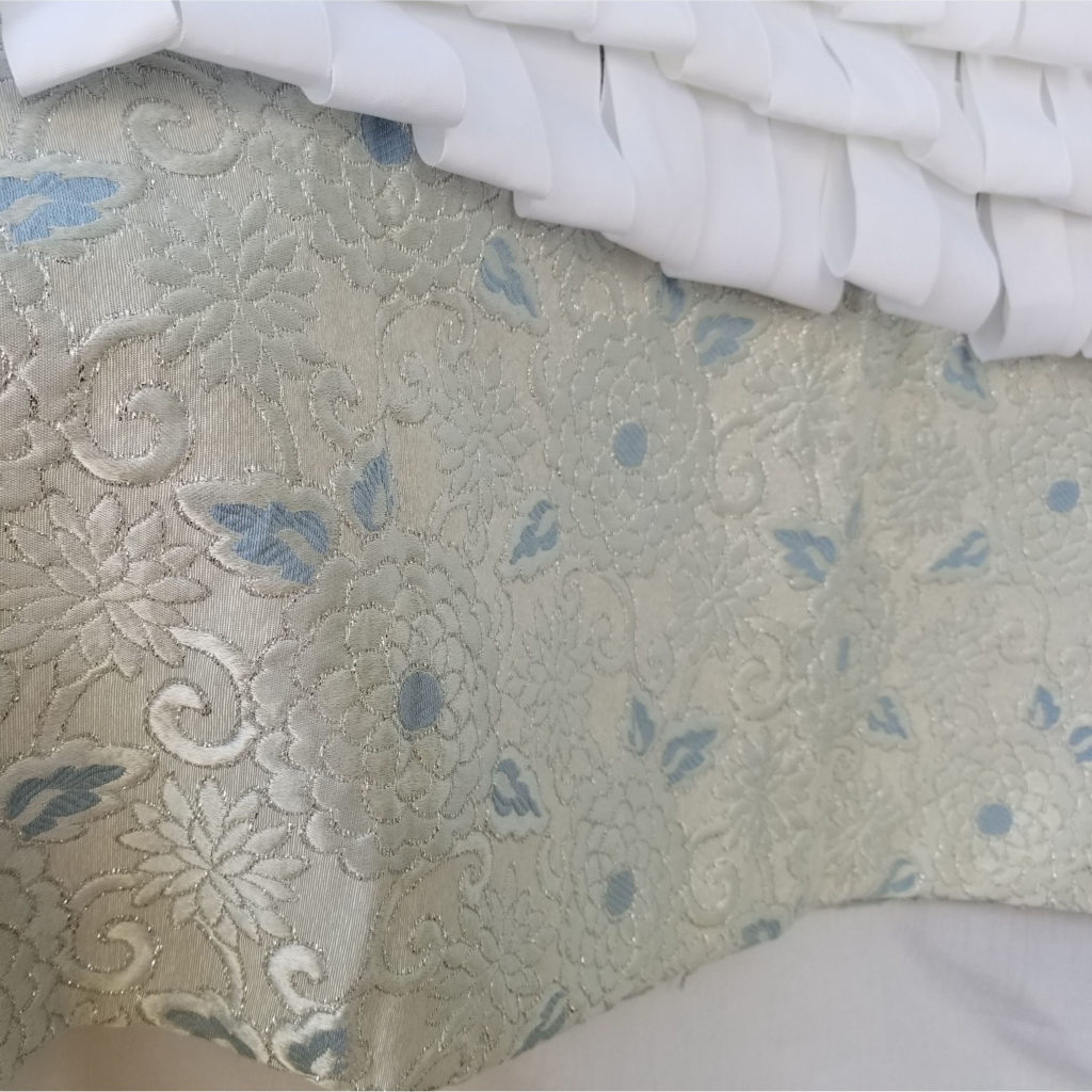 A closeup of icy blue and white brocade fabric