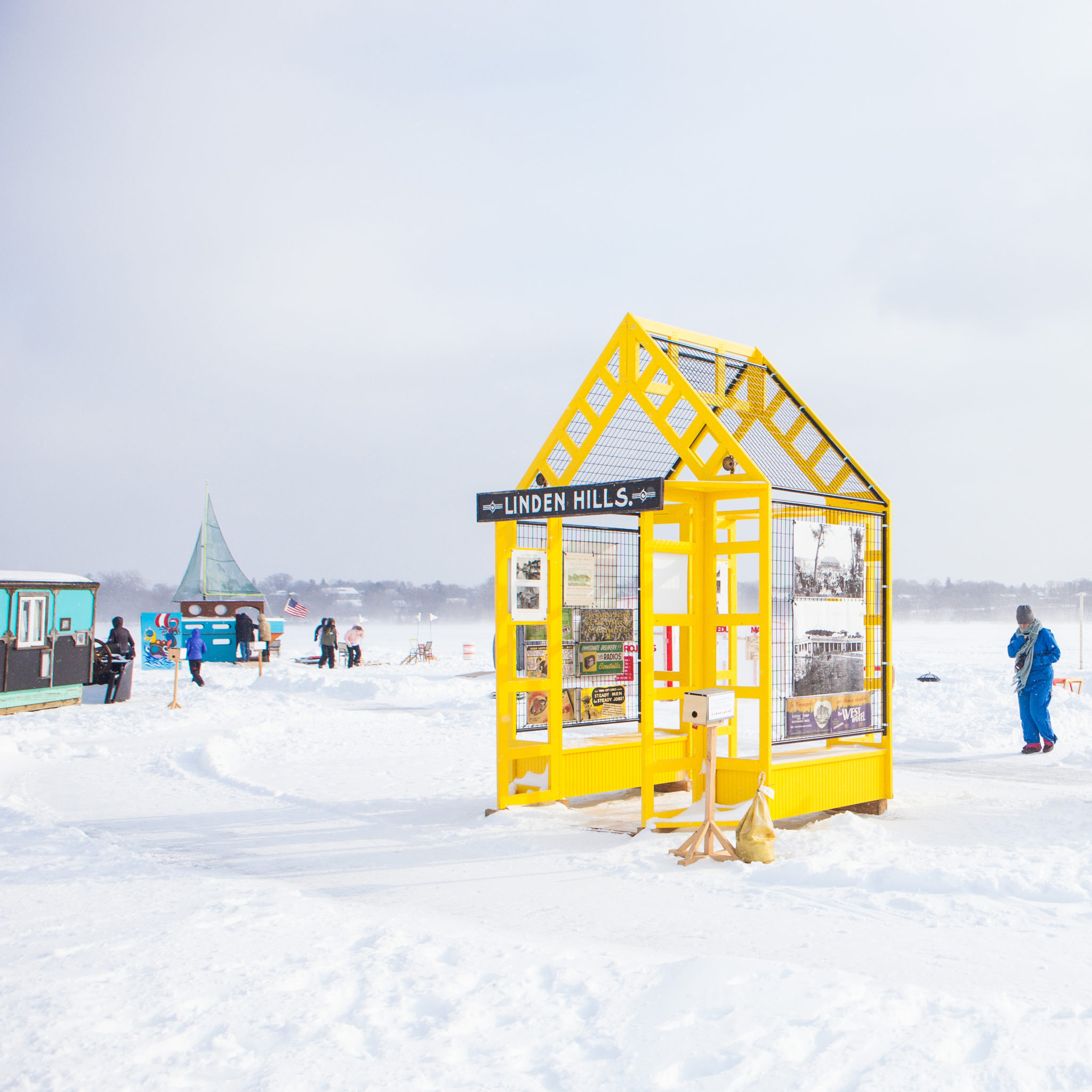 A yellow arched structure is featured in the shanty village on a snowy day