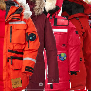 An image of a row of winter safety parkas with furry hoods in oranges and reds