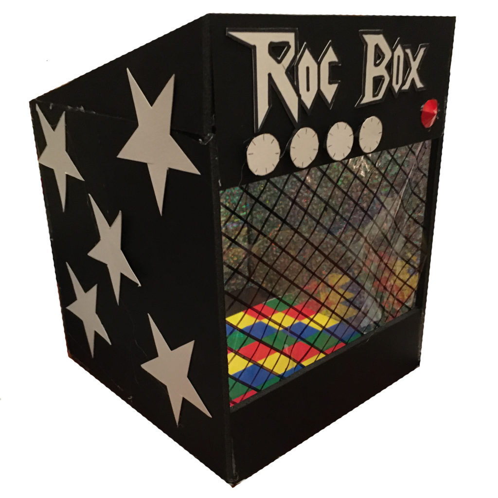 A model of a shanty that looks like an amp. it has silver stars on the side, big knobs on the front under the words 'roc box'