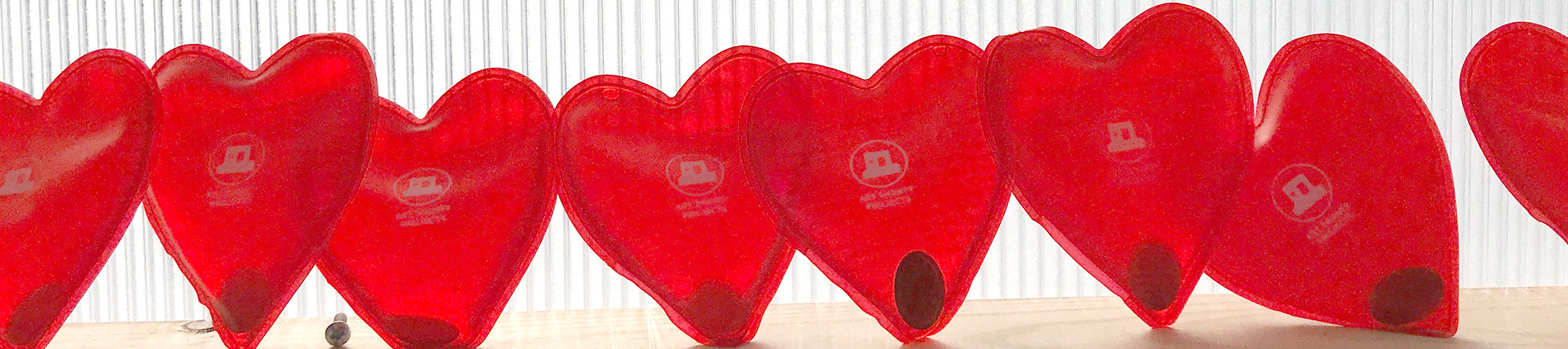A row of red heart-shaped hand warmers with Art Shanty Projects logo on them