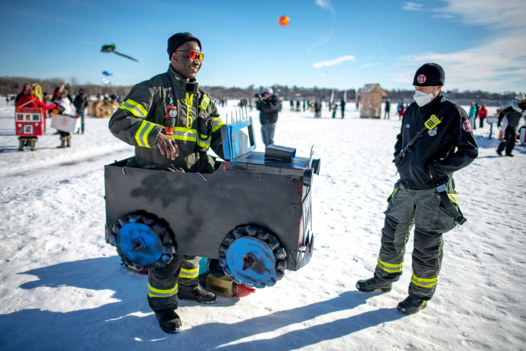 a firefighter poses in a wearable art car