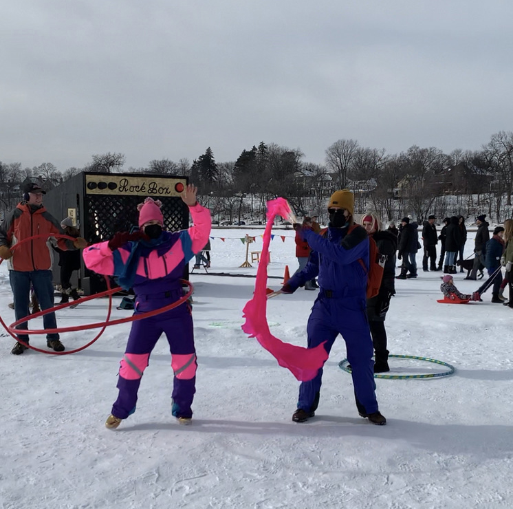 People in fantastic snowsuits practice flow arts in the shanty village.