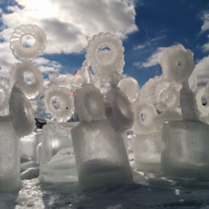Sunlight shines through a series of ice sculptures. Blue skies in the background.