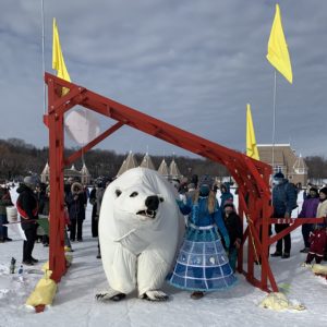 A life size polar bear puppet walks through the art shanty gate