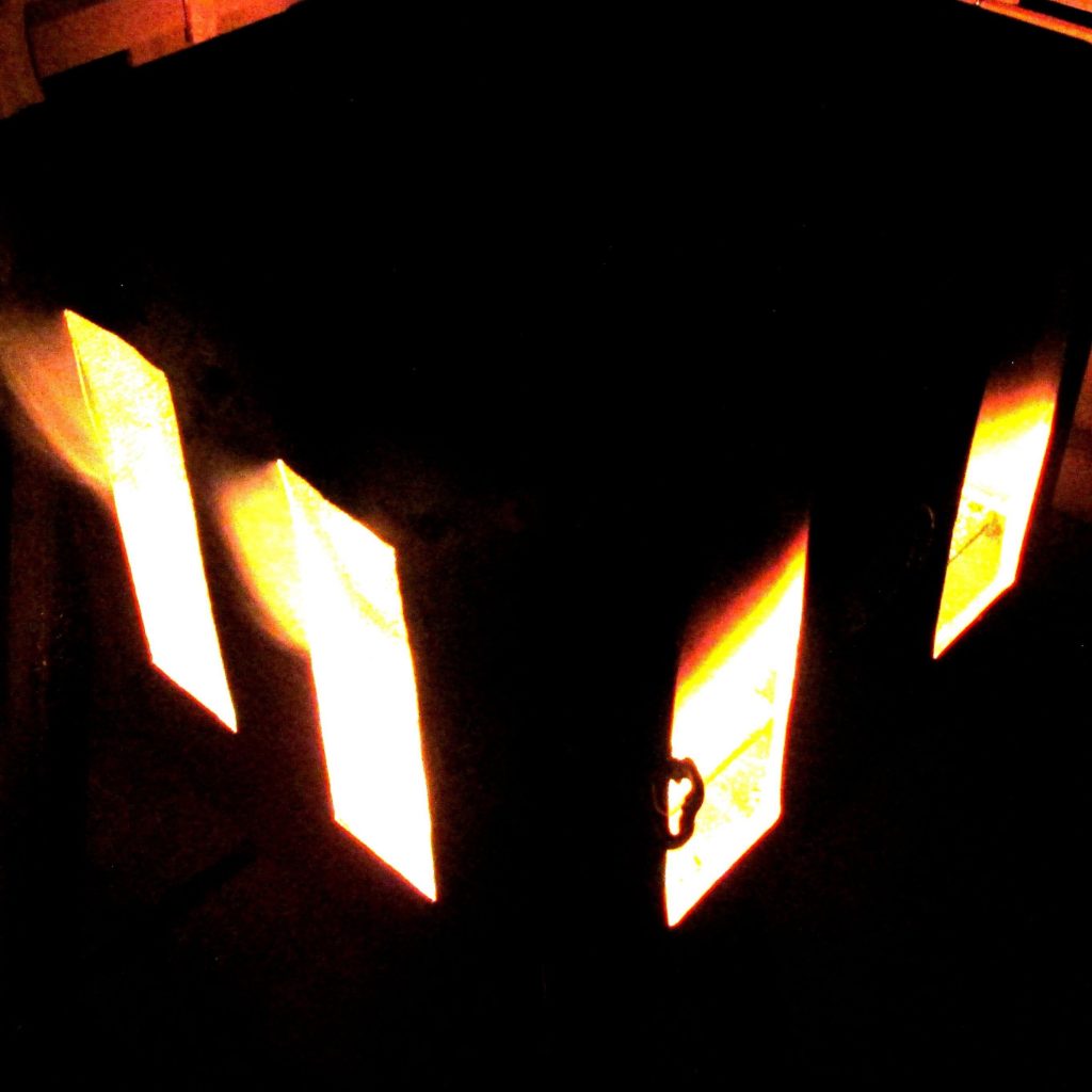 fire burning inside a box peeks through four vertical rectangular openings