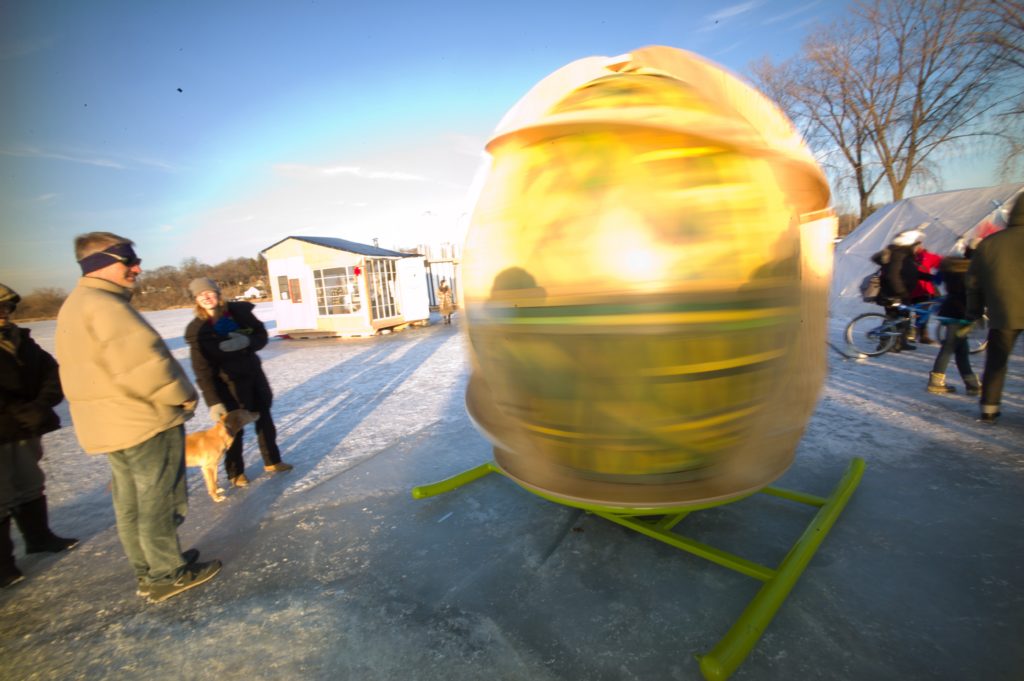 people look at a blurry yellow orb spinning against the backdrop of a shanty village