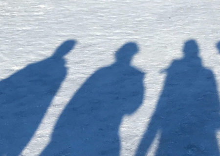 the shadows of 3 people darken the snow