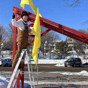 Board Member Sarah Wirth puts up a yellow flag on the red shanty gate