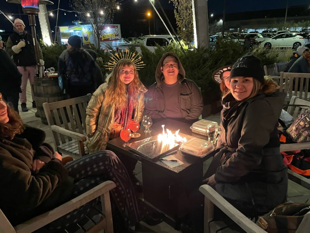 Three babes sitting next to a fire pit at the Member Party