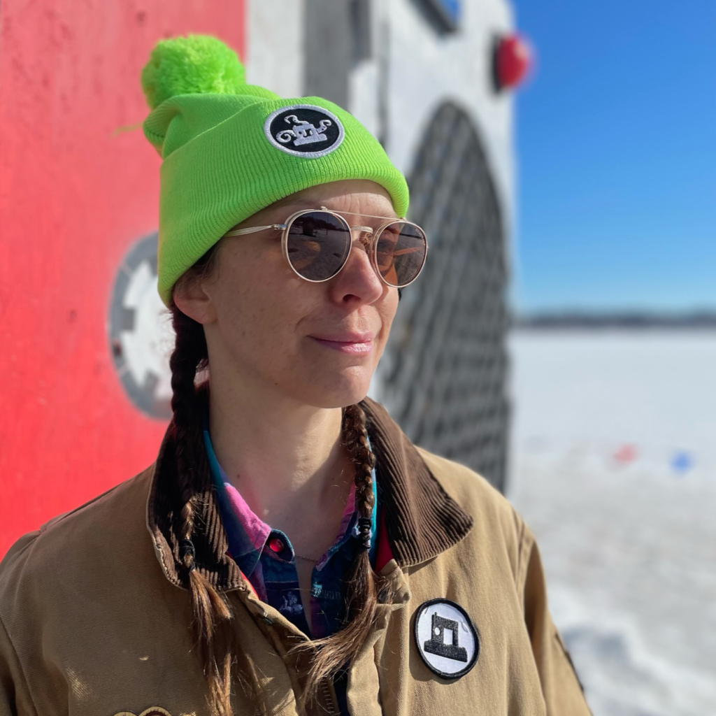 Artistic Director Erin wearing a lime green Art Shanty lake monster hat