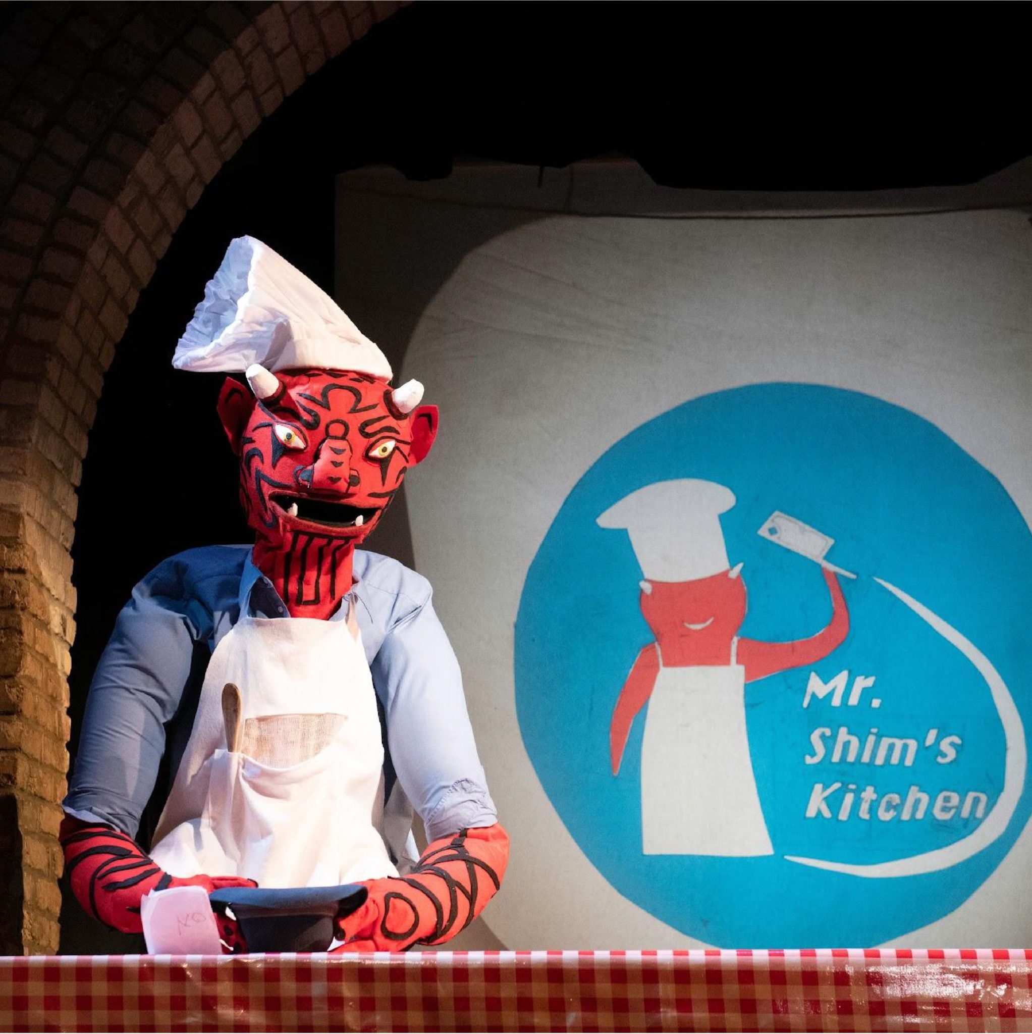 a puppet in front of a sign that reads 'mr. shim's kitchen'