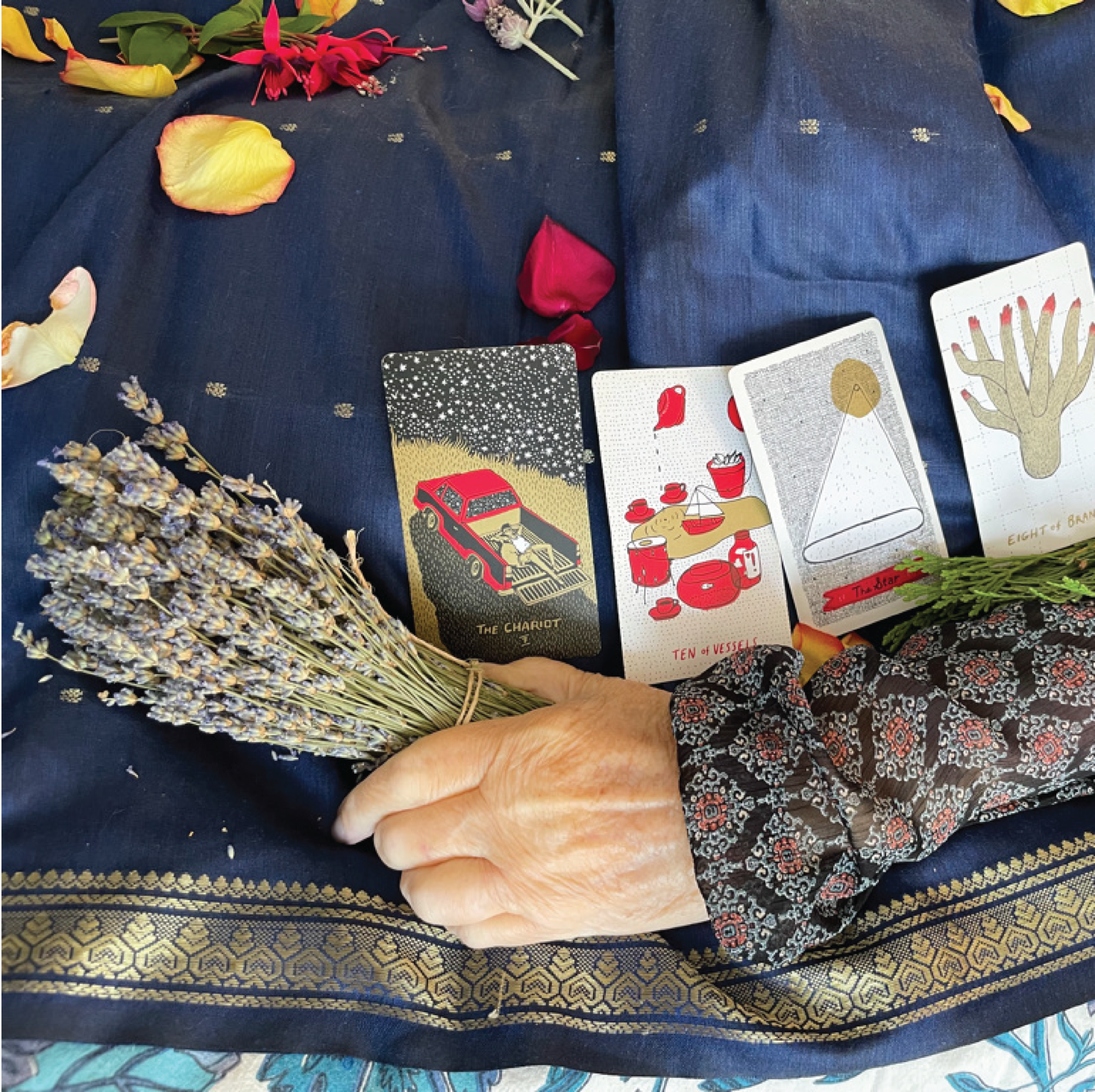 a hand holding a bundle of lavender with tarot cards resting on their body