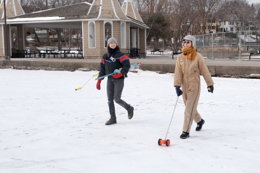 two people set out with tools to measure ice