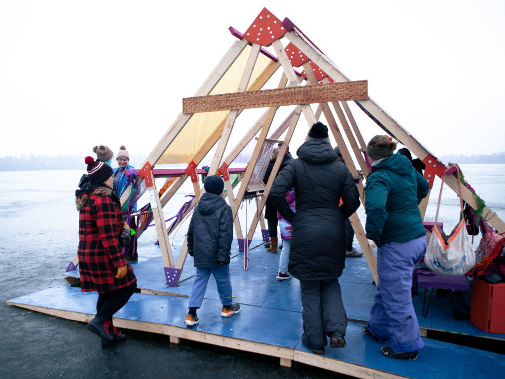 people weave onto an open air truss structure