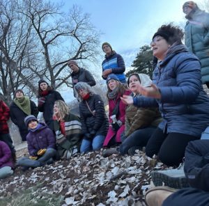 A group of people kneeling in the snow singing