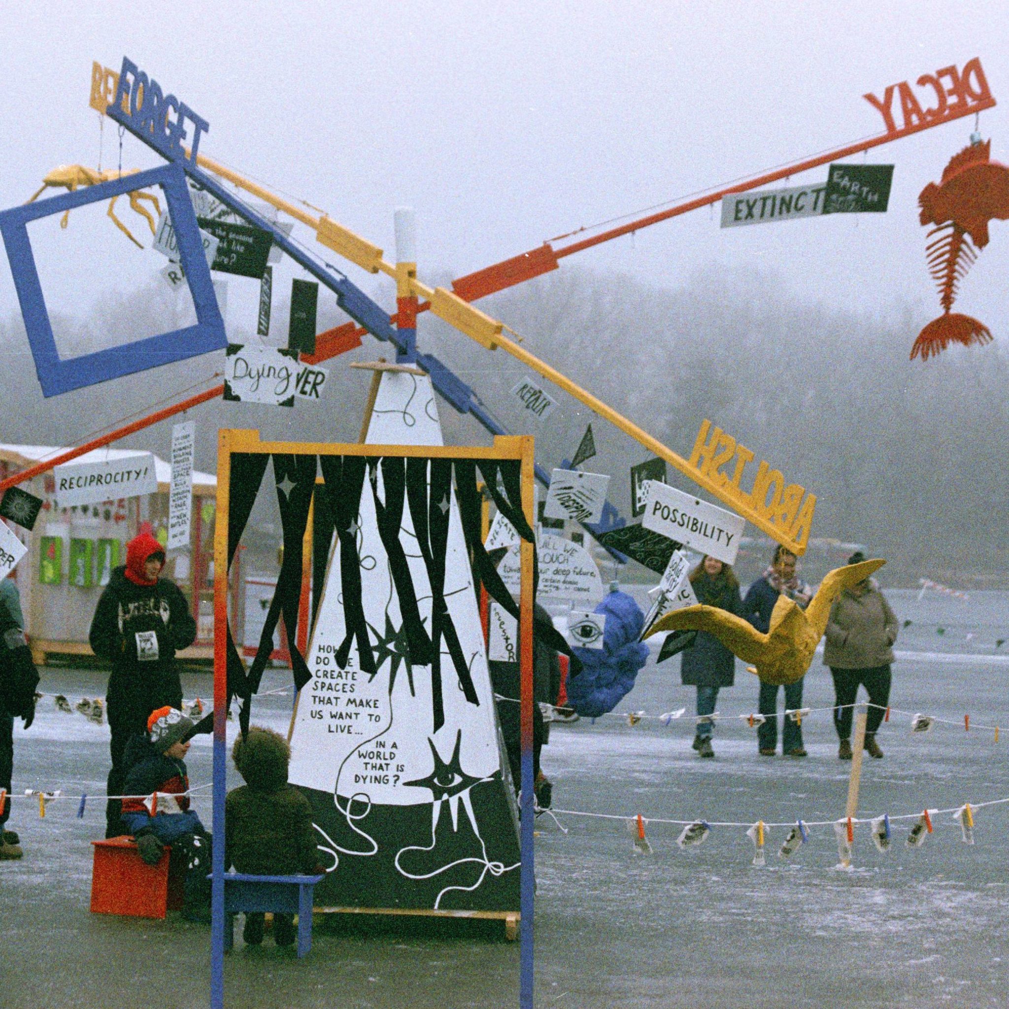 A giant colorful mobile in action on a frozen lake against a backdrop of foggy air.