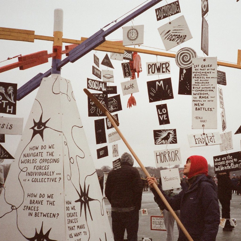 a person uses a long pole with a hook on the end to hang something onto a giant mobile.