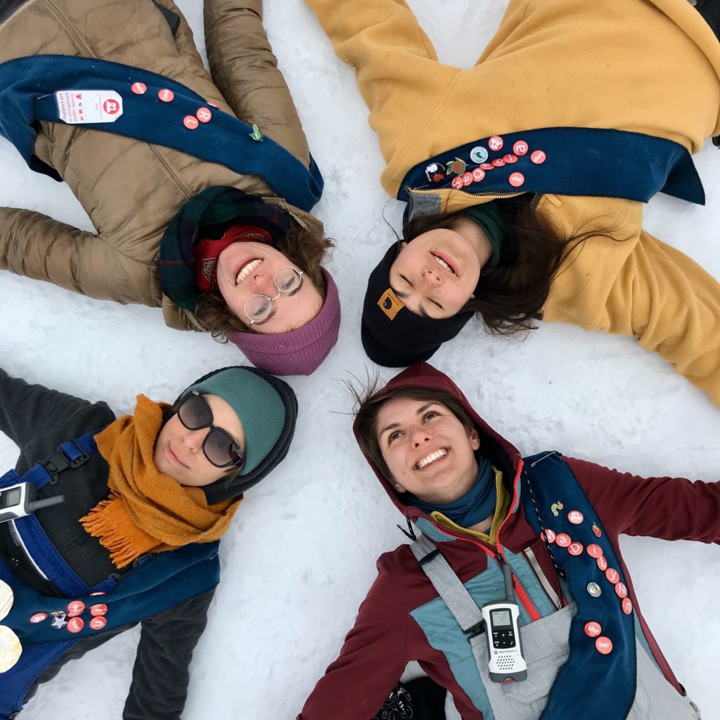 Four people lay in the snow smiling.