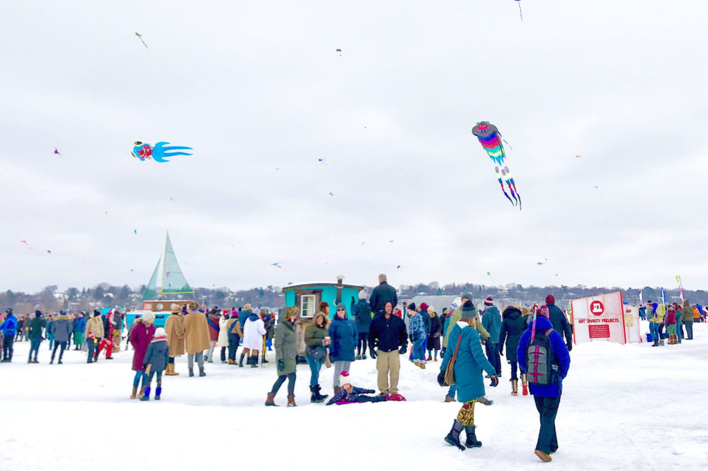 a vibrant shanty village full of people with kites flying overhead