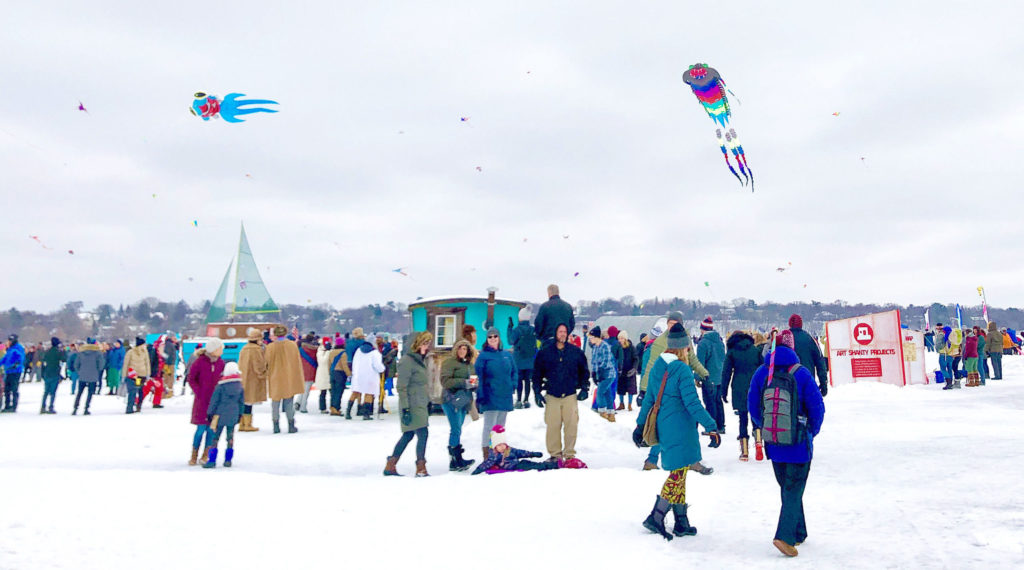 a vibrant shanty village full of people with kites flying overhead