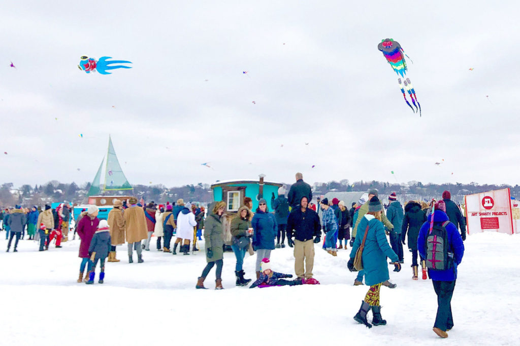 a vibrant shanty village full of people with kites flying overhead