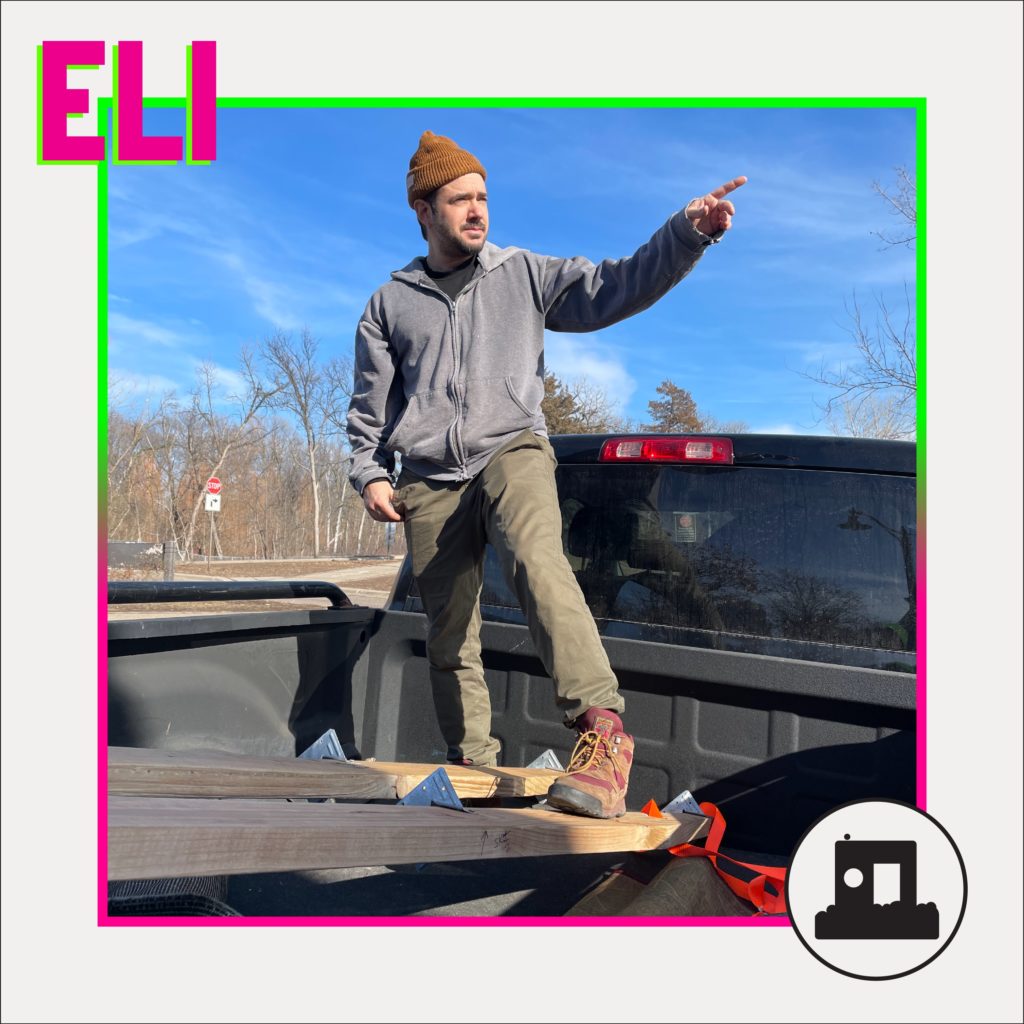 a person stands in the bed of a pickup truck and points towards the right