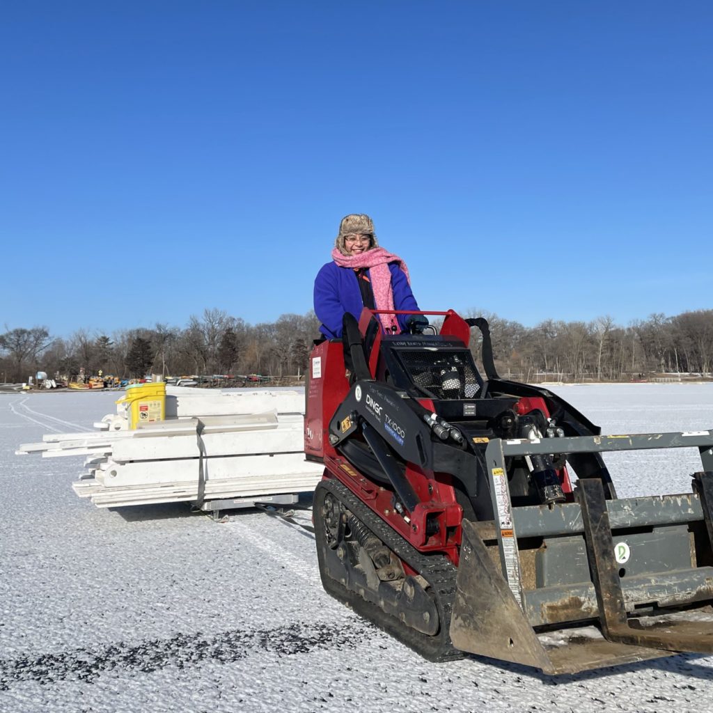 a person drives a dingo pulling a shanty across the frozen lake