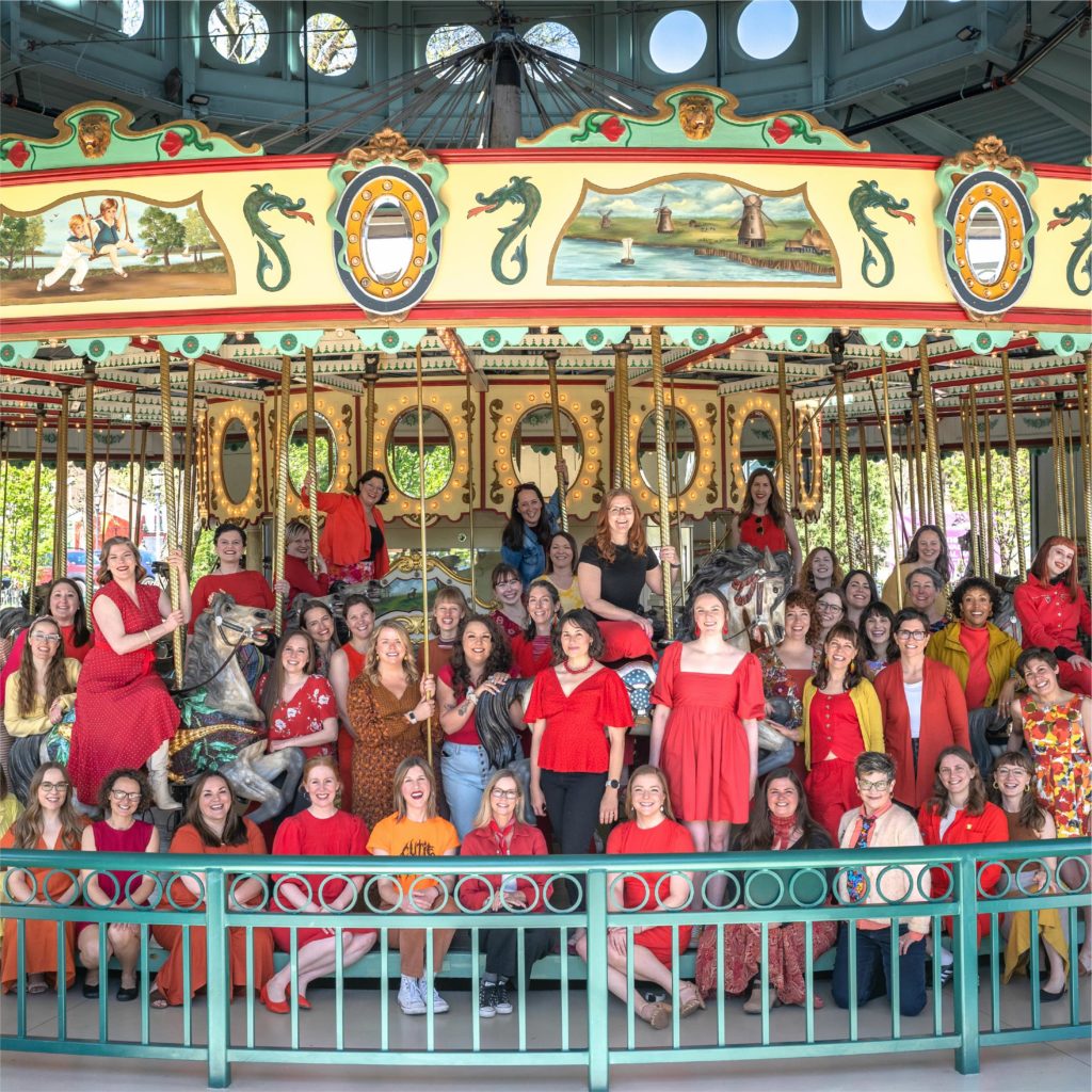 A group of people dressed in fiery colors poses on a carousel