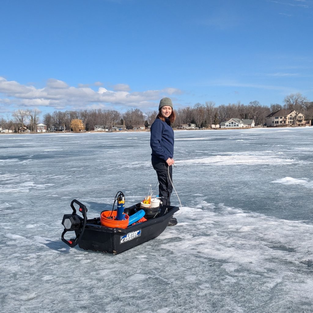 A person pulls a utility sled full of scientific gear across a frozen lake