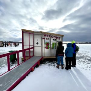 a view of three people at the welcome shanty looking in merch displays