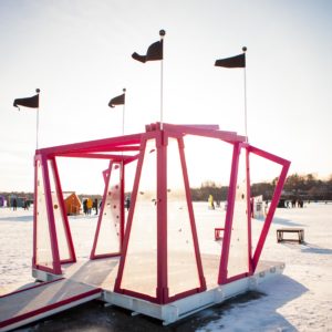 a photo of a stage with magenta beams, translucent walls and black flags flying above