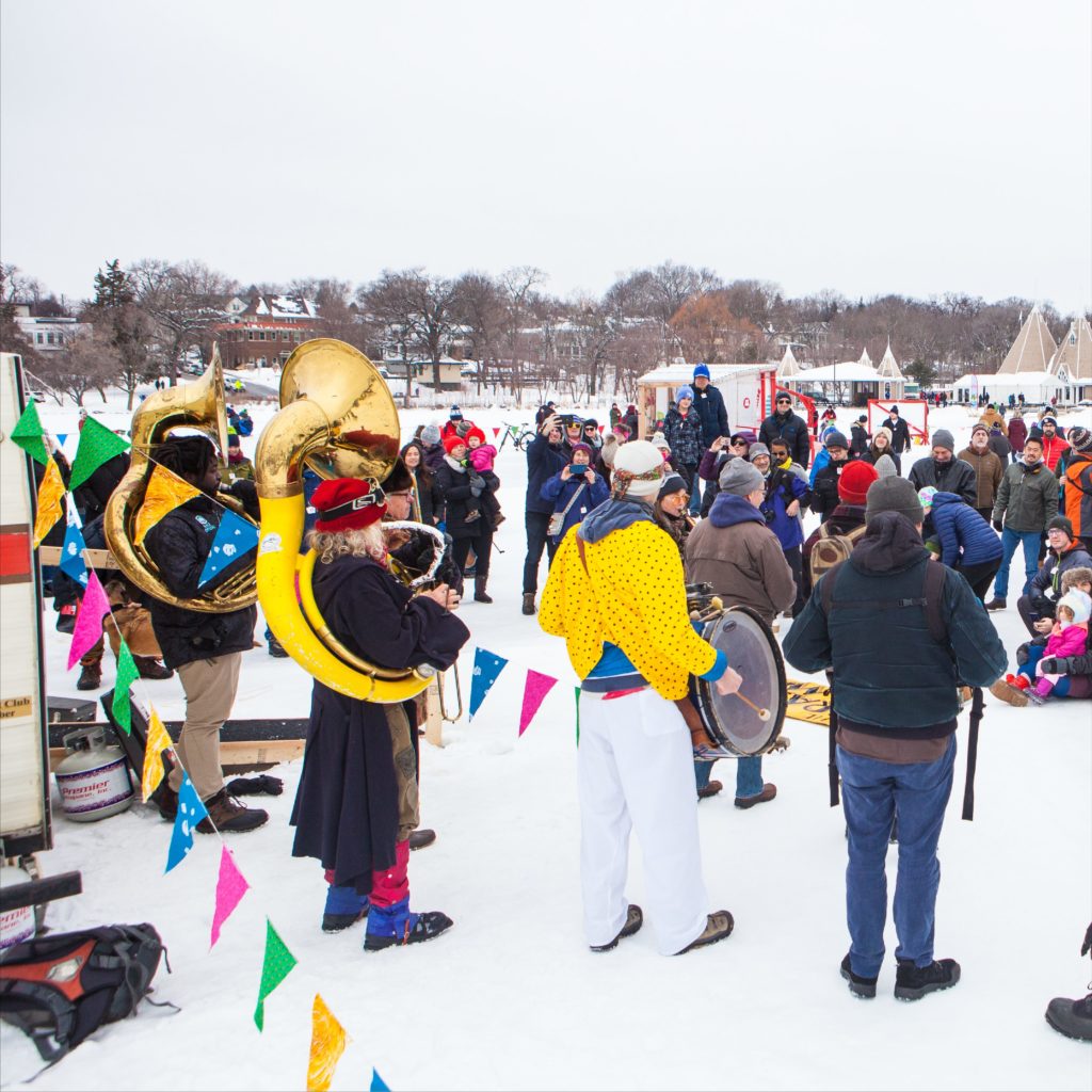 a band plays brass instruments as a large crowd looks on