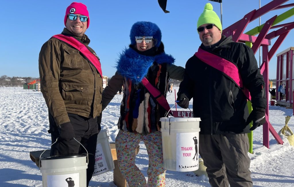 three volunteers with big smiles and dark sunglasses at the shanty village entrance