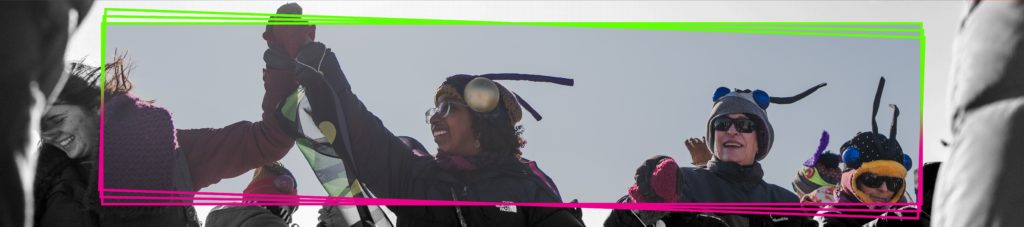 adults wearing colorful pollinator wings and antenna dance outside in the winter shanty village