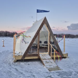 An A-frame shanty with a transparent front wall and little flag flying above