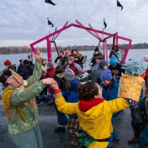 A photo of a crowd doing a traditional dance while a klezmer band plays live on the outdoor art shanty stage